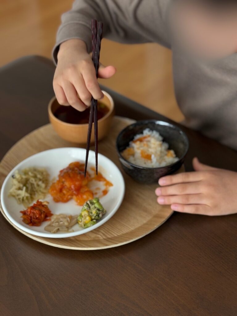 ワタミの宅食ダイレクトのおかずをお皿に盛り付けてご飯と一緒に食べている子どもの食卓風景