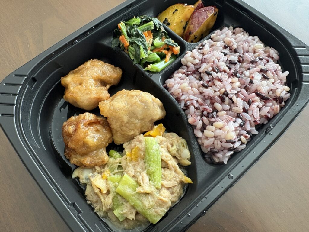 ママの休食の容器全体を斜めから撮影（黒米ごはん・唐揚げ・副菜）