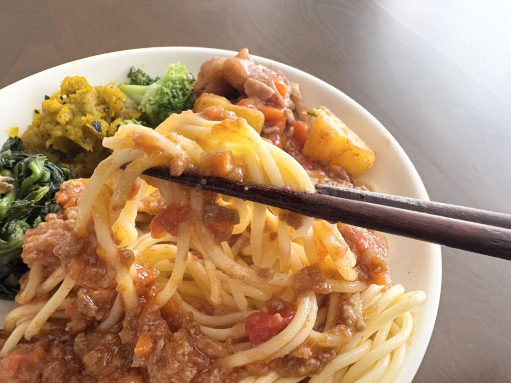 ママの休食のボロネーゼスパゲッティを箸で持ち上げたアップの実食写真