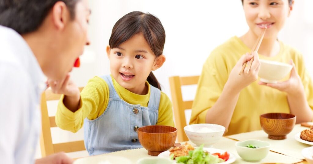 家族で食卓を囲んで食事をしているイメージ写真