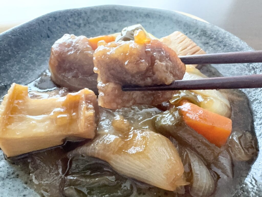 わんまいるの肉料理を箸で持ち上げた実食写真