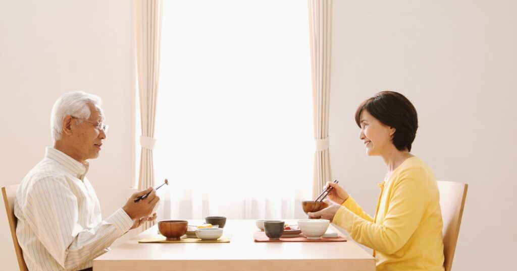 高齢のご夫婦が食卓で食事をしているイメージ写真