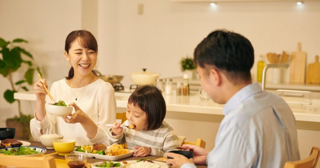 家族で食卓を囲んで食事をしているイメージ写真